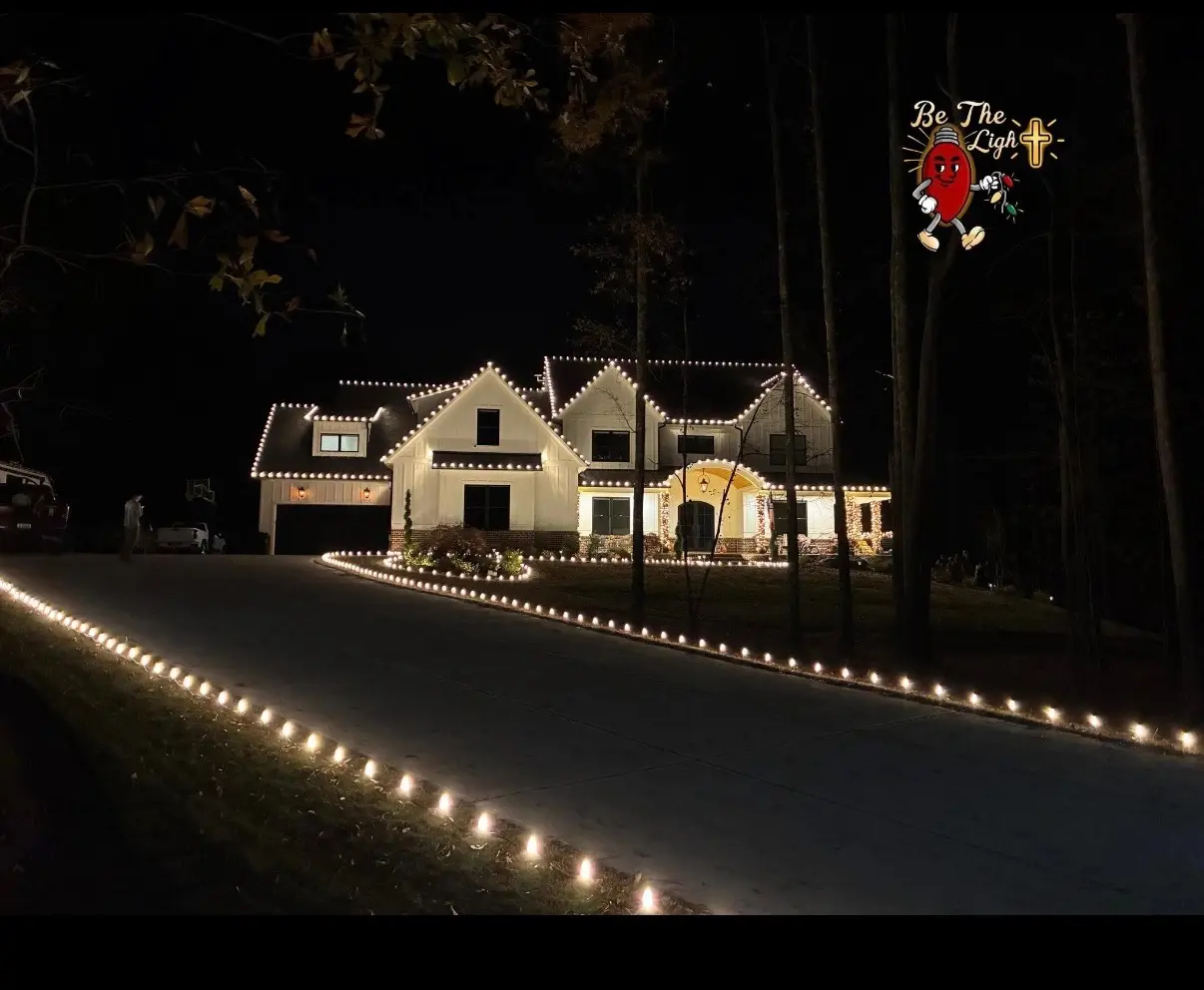 White farmhouse with warm white roofline and driveway Christmas lights by Be The Light GA